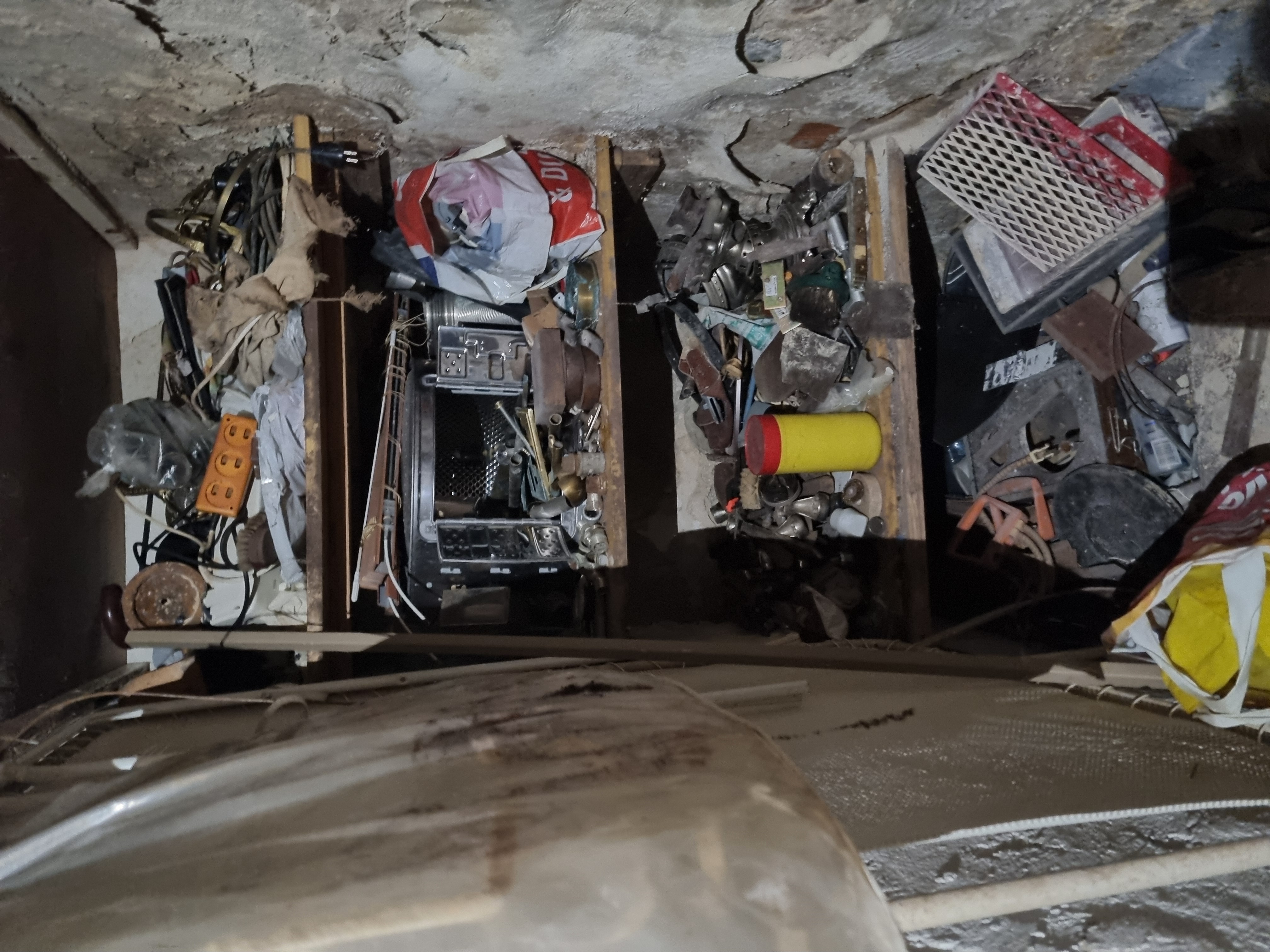 Opróżnianie piwnicy przed – zagracona przestrzeń z półkami i odpadami